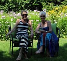 Two senior women sitting in lawn chairs smiling. 