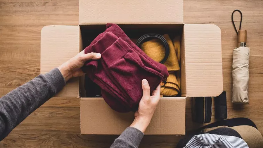 Photo of hands placing items in a cardboard box