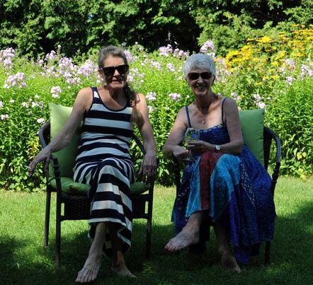 Two senior women sitting in lawn chairs smiling. 